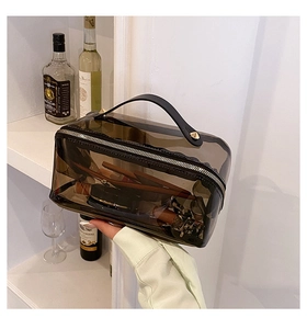 Detailansicht der dunkeltransparenten PVC-Kosmetiktasche mit Griff und Goldbeschlägen