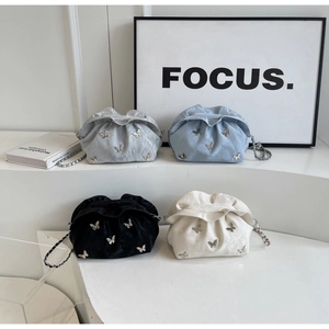 Detail of pleated bucket bags in multiple colors featuring metal butterfly accents
