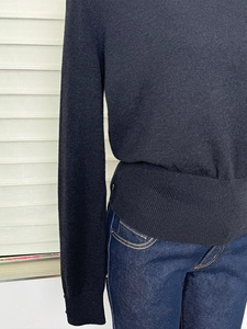 Detail of waist-slimming wool knit top showing fabric texture and ribbed cuff design