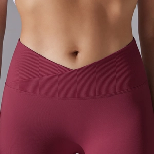 Detailed close-up of dark red seamless yoga pants featuring a cross V-waist and ribbed fabric