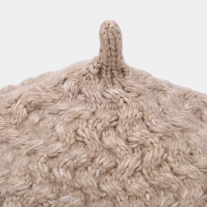 Close-up of cable knit texture and top stalk detail on a light khaki wool beret