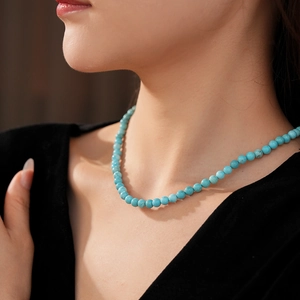 Close-up of minimalist turquoise beaded necklace on model with vintage Chinese style