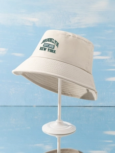 Close-up of green Brooklyn embroidery on a beige cotton bucket hat with detailed stitching