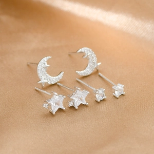 Macro shot of silver crescent moon and star stud earring set on champagne silk fabric