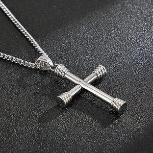 Close-up of a silver cross pendant with dumbbell ends on a stylish Cuban link chain