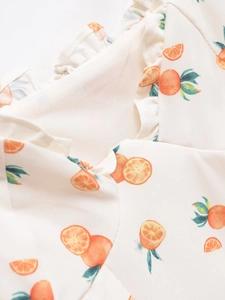 Détail du volant et de l'imprimé orange sur une robe en coton tissé blanc de qualité