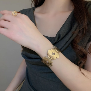 Detailed close-up of golden leaf butterfly bracelet and ring set on model wrist