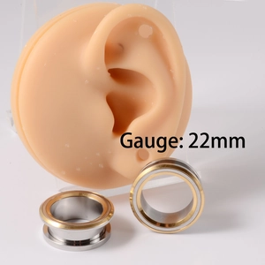 Macro detail of 22mm gold and silver stainless steel ear gauge expander on ear model
