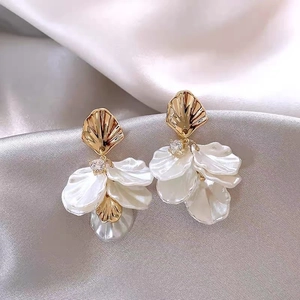Detail of layered pearl petals and shell clasp on gold earrings over silk cloth