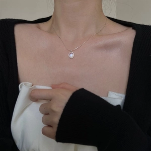 Elegant silver snake chain necklace with blue moonstone oval pendant on a female model
