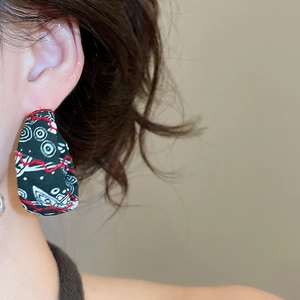 Gros plan de boucles d'oreilles en tissu avec motif spirale et coutures rouges