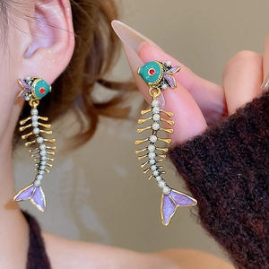 Detail of fishbone drop earrings with blue enamel and white pearls on golden frame