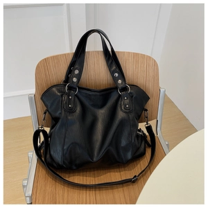 Detail of black leather tote bag with silver rivets and studs on a wooden chair