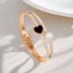 Detail of rose gold titanium bracelet with black and white heart charms and pavé zircon