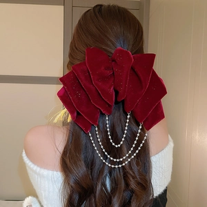 Elegant red velvet bow hair clip with pearl chain tassels on a model hair bun