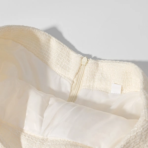 Dettaglio della trama in tweed crema e della cerniera invisibile sulla gonna elegante