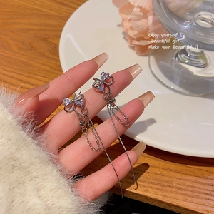 Detail of silver bow tassel earrings with micro-set zircons held by hand