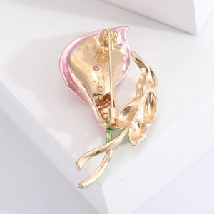 Pink enamel flower brooch in gold-plated metal with secure pin clasp on a white stand