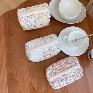 Detailed view of three quilted floral cosmetic bags on a rustic wooden table setting