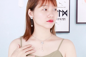 Detail of silver pearl necklace and earrings set with LOVE engraving on a model