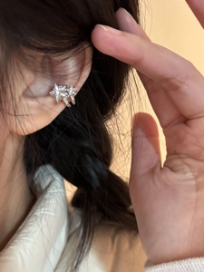 Close-up of a silver star ear cuff with zircon stones worn on the ear cartilage