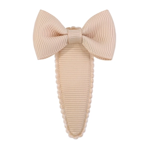 Detailed view of beige grosgrain ribbon bow hair clip with scalloped edge and covered base