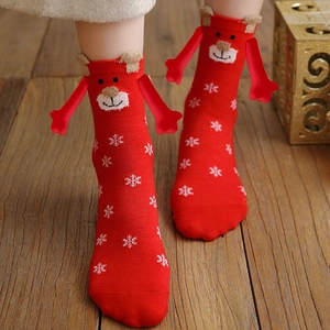 Detail of red Christmas socks with reindeer character and 3D magnetic hands on wood