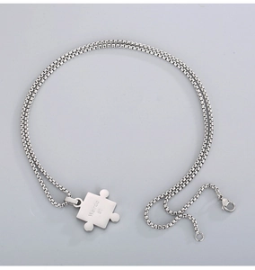 Close-up of puzzle piece necklace in silver stainless steel with box chain and lobster clasp