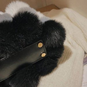 Close-up of plush faux fur handbag featuring luxury metal buckle and leather trim detail