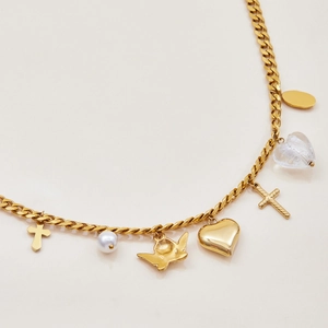 Close-up of golden Cuban link necklace featuring heart, cross, and pearl charms