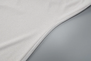Gros plan sur la texture du tissu blanc côtelé montrant le tissage vertical doux de la robe