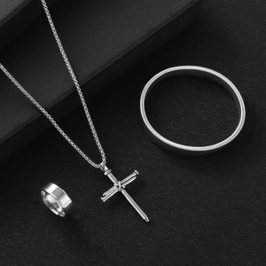 Macro view of silver cross necklace, minimalist ring, and textured cuff bracelet set
