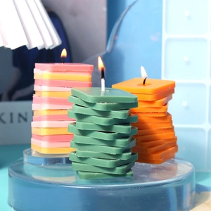 Primer plano de tres velas aromáticas cuadradas apiladas en soporte de acrílico azul