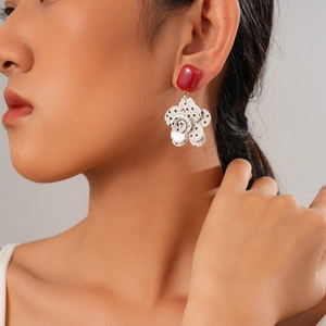 Close-up of a floral dangle earring with a red stud and black-and-white polka dot petals
