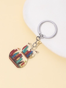 Detail of a cat-shaped acrylic keychain with a bookshelf pattern on a beige surface