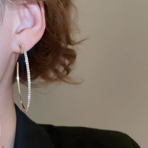 Close-up of sparkling gold hoop earrings with pavé rhinestones worn by a model