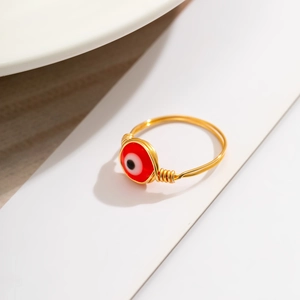 Detailed macro view of handmade gold wire-wrapped ring with a red evil eye bead