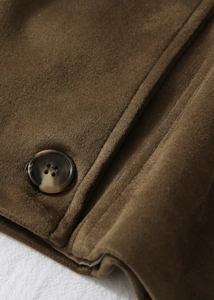 Détail du tissu en suédine marron avec bouton en résine marbrée pour manteau femme