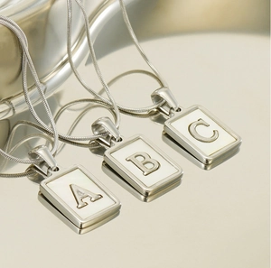Macro shot of silver square pendants A, B, and C with shell inlay on snake chains