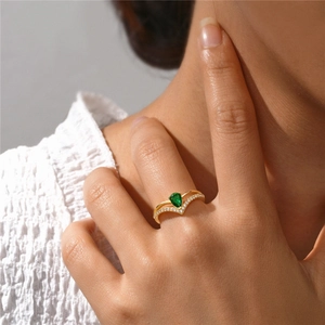 Close-up of golden s925 silver double-ring with green teardrop stone and pavé diamonds