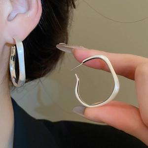 Close-up of irregular silver-plated hoop earrings with a matte brushed metallic texture