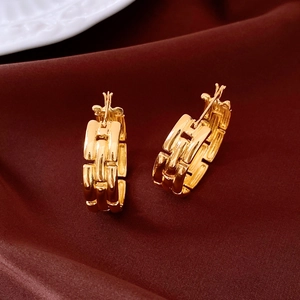 Detail of gold-plated geometric link hoop earrings on a dark red satin background