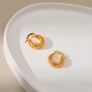 18K gold plated hoop earrings with textured woven pattern on white ceramic plate