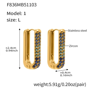 Detailed macro view of U-shaped golden earrings with gradient blue to green zircon stones