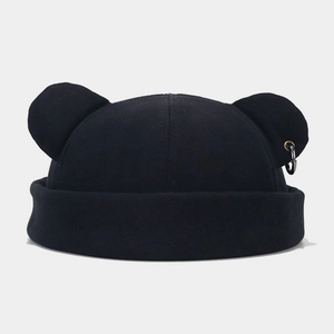 Detail of black brimless docker cap featuring bear ears and a silver metal ring accessory