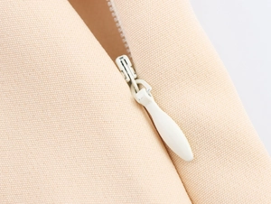Detailed macro view of high-quality white zipper and beige canvas fabric on skort