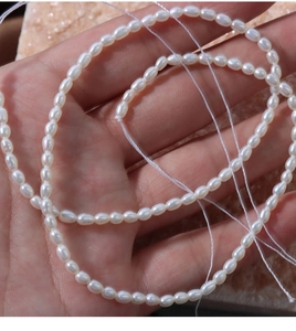 Macro shot of 4mm natural white freshwater seed pearls held in hand for DIY jewelry