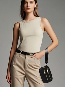 Detail view of a black multi-zipper wristlet wallet held by a model in casual wear