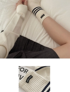 Close-up of cream ribbed mid-calf socks with three black stripes and woven label
