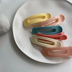 Detail of six large matte duckbill hair clips in Morandi colors on a ceramic tray